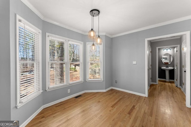 unfurnished dining area with crown molding, light wood finished floors, visible vents, and baseboards