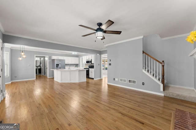 unfurnished living room with light wood finished floors, visible vents, baseboards, ceiling fan, and stairs