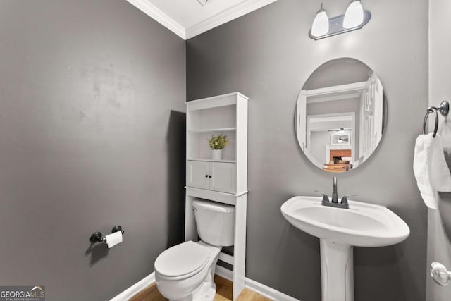 half bathroom with toilet, baseboards, and ornamental molding