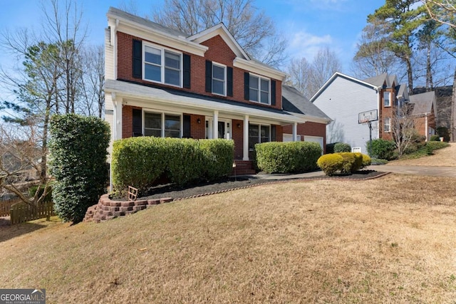 view of front facade with a porch, a front yard, brick siding, and a garage