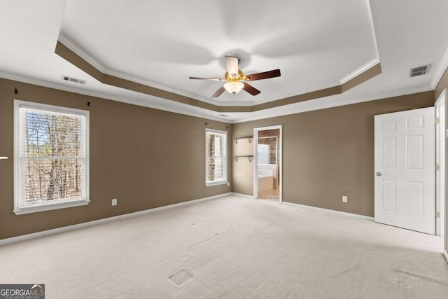 unfurnished bedroom with a tray ceiling, visible vents, light carpet, and baseboards