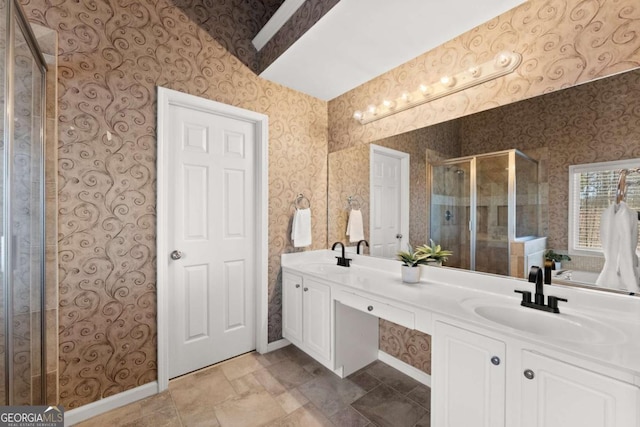 bathroom with double vanity, a stall shower, a sink, and wallpapered walls