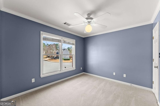 spare room with carpet floors, visible vents, a ceiling fan, baseboards, and crown molding