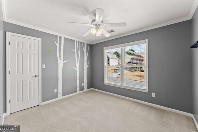 carpeted spare room featuring ornamental molding, a ceiling fan, and baseboards