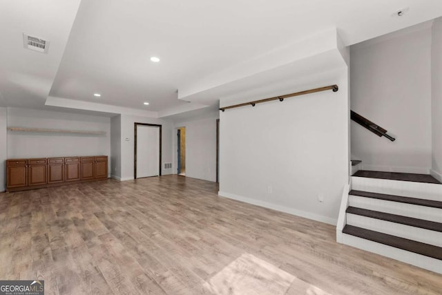 unfurnished living room with light wood-type flooring, visible vents, recessed lighting, and stairs