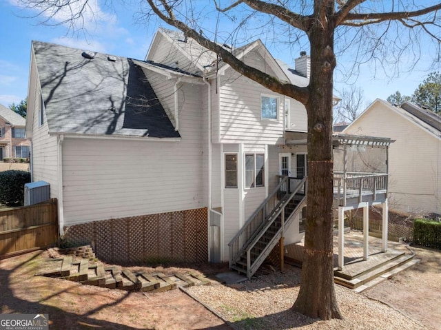 rear view of house with roof with shingles, fence, a deck, a pergola, and stairs