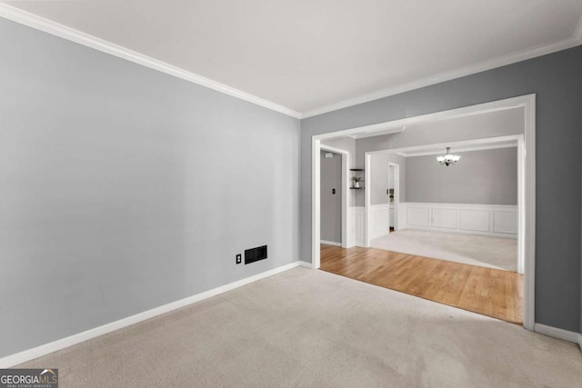 carpeted empty room with an inviting chandelier, baseboards, and crown molding