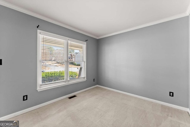 spare room with baseboards, ornamental molding, visible vents, and light colored carpet