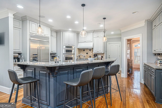 kitchen with crown molding, wood finished floors, tasteful backsplash, and appliances with stainless steel finishes