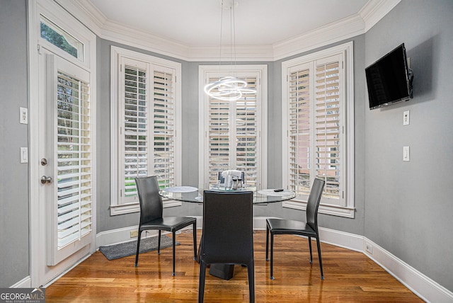 dining area featuring crown molding, wood finished floors, and baseboards