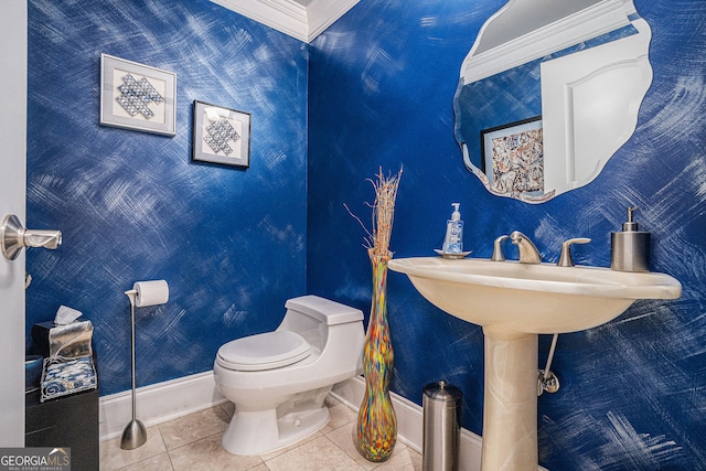 half bathroom featuring baseboards, toilet, crown molding, and tile patterned flooring