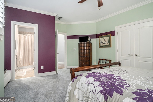 carpeted bedroom with visible vents, baseboards, ornamental molding, a closet, and ensuite bath