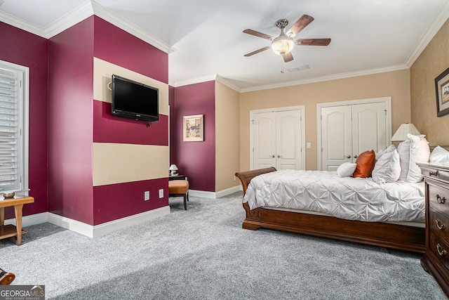 carpeted bedroom featuring visible vents, baseboards, two closets, and ornamental molding