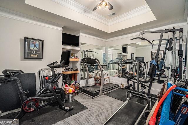 gym featuring a ceiling fan, a tray ceiling, crown molding, and visible vents