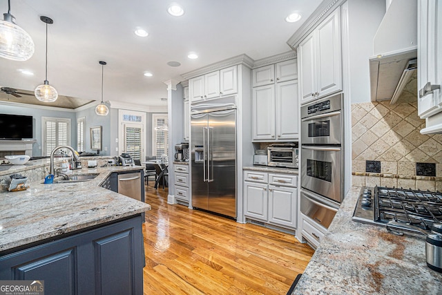 kitchen featuring a warming drawer, light wood-type flooring, a sink, open floor plan, and stainless steel appliances