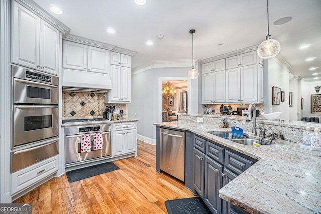 kitchen with a sink, stainless steel appliances, crown molding, a warming drawer, and exhaust hood