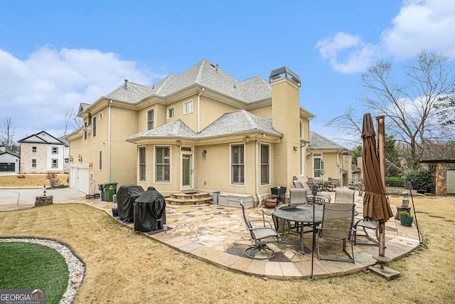 back of house with concrete driveway, stucco siding, a chimney, a garage, and a patio area