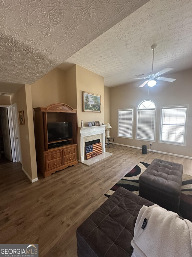 living area featuring a ceiling fan, lofted ceiling, wood finished floors, a textured ceiling, and a high end fireplace