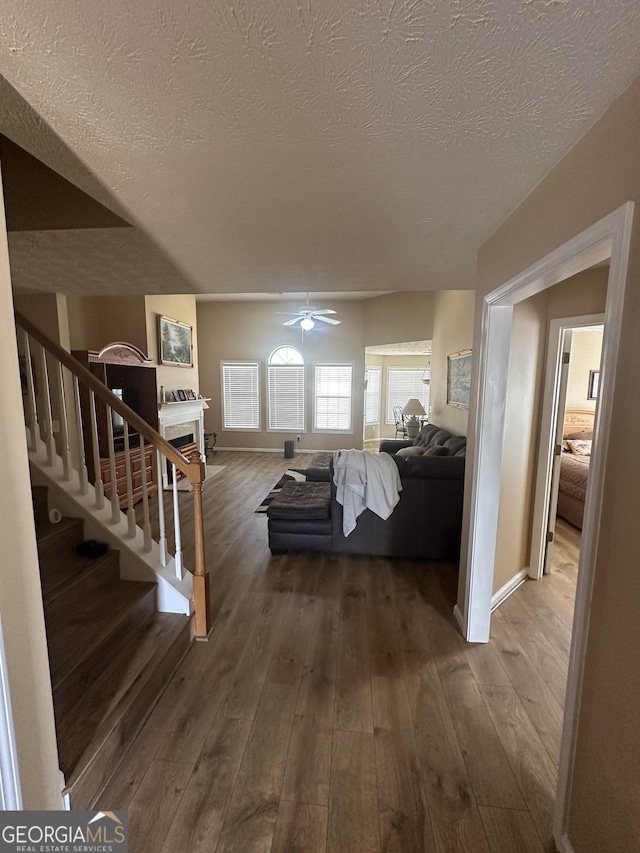 living area with stairs, a ceiling fan, a fireplace, and hardwood / wood-style flooring