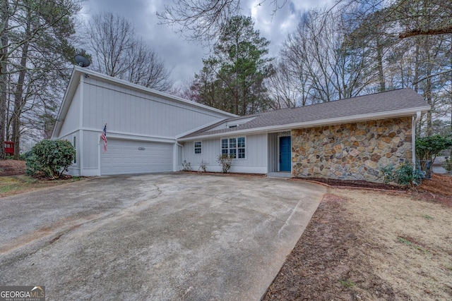 view of front facade featuring a garage, driveway, and stone siding