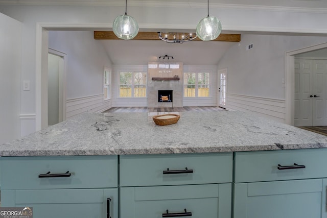 kitchen featuring light stone counters, open floor plan, vaulted ceiling with beams, and a premium fireplace