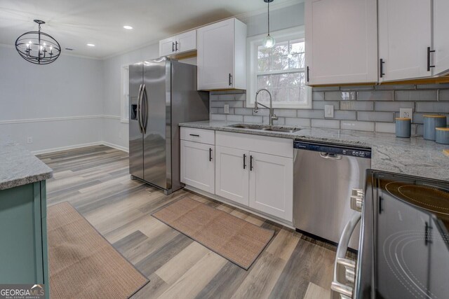 kitchen with tasteful backsplash, light wood-style flooring, appliances with stainless steel finishes, white cabinetry, and a sink