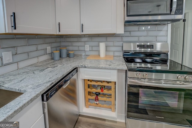 kitchen featuring appliances with stainless steel finishes, backsplash, light stone counters, and white cabinets