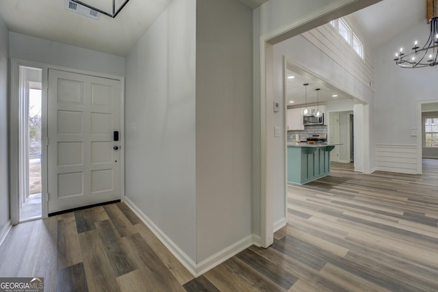 foyer with a chandelier, visible vents, baseboards, and wood finished floors