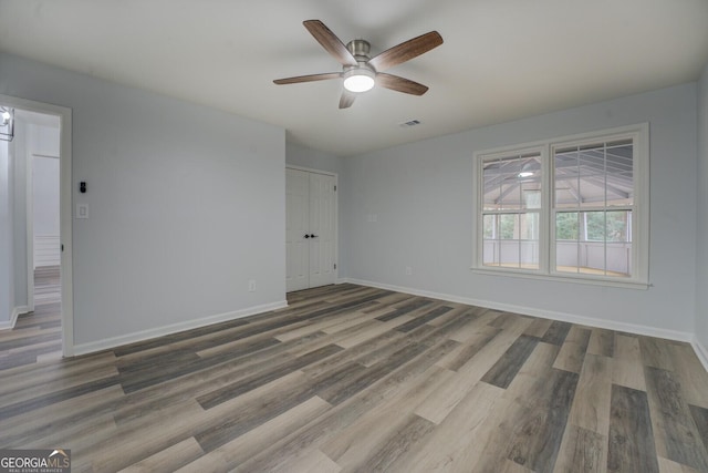 unfurnished room featuring ceiling fan, wood finished floors, visible vents, and baseboards