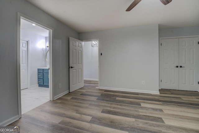 unfurnished bedroom featuring a closet, baseboards, connected bathroom, and wood finished floors