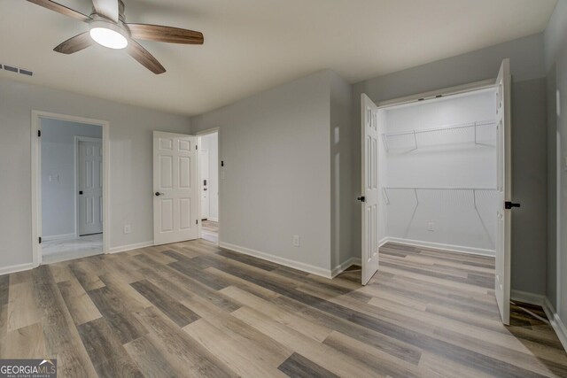 unfurnished bedroom with ceiling fan, wood finished floors, visible vents, and baseboards