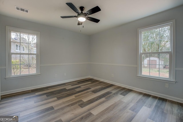 unfurnished room featuring baseboards, visible vents, ceiling fan, and wood finished floors