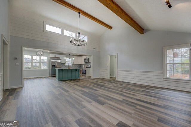 unfurnished living room with a chandelier, dark wood-style flooring, beamed ceiling, and high vaulted ceiling