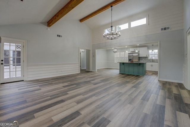 unfurnished living room featuring wood finished floors, a sink, visible vents, and a notable chandelier