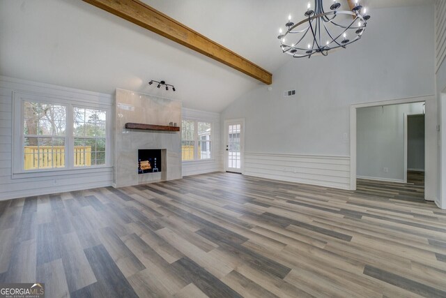 unfurnished living room featuring high vaulted ceiling, a premium fireplace, wood finished floors, visible vents, and beamed ceiling