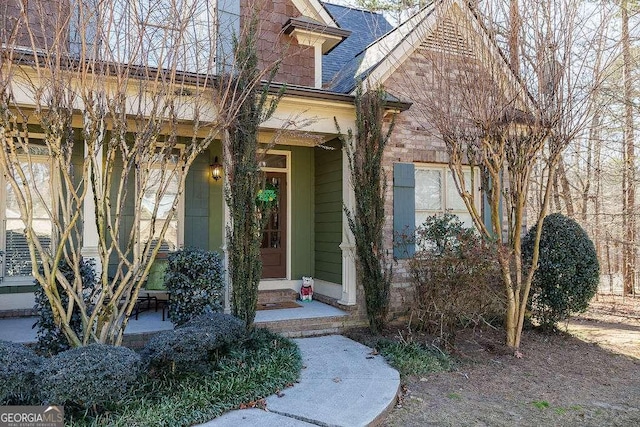 view of exterior entry featuring roof with shingles