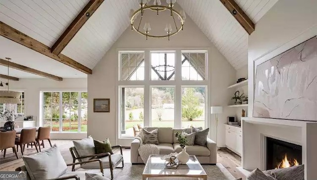 living room with high vaulted ceiling, a warm lit fireplace, a chandelier, and beamed ceiling