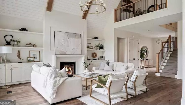 living room with stairs, a lit fireplace, built in shelves, and wood finished floors