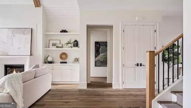 interior space featuring stairs, wood finished floors, a glass covered fireplace, and built in features