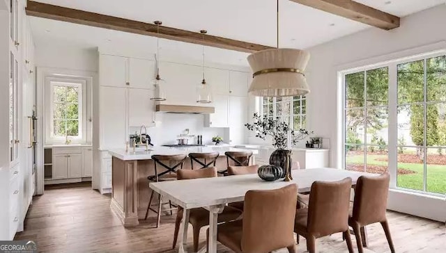 dining space with light wood-type flooring and beam ceiling