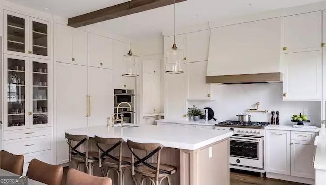 kitchen with beam ceiling, a breakfast bar area, light countertops, appliances with stainless steel finishes, and white cabinetry