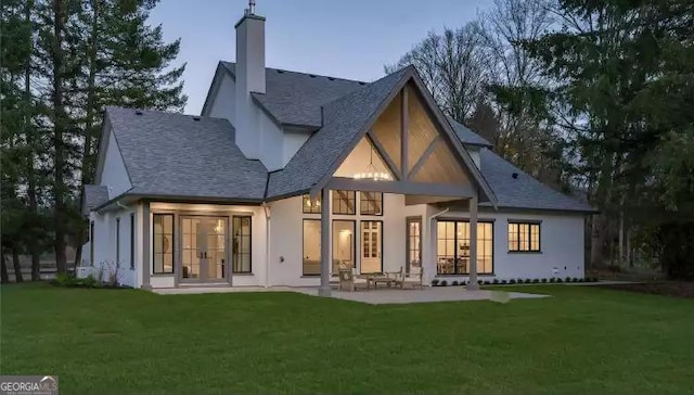 rear view of house with a patio, french doors, a lawn, and a chimney