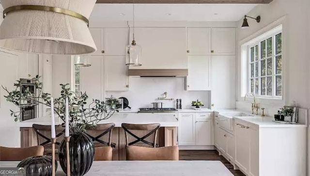 kitchen featuring pendant lighting, light countertops, a sink, and white cabinetry