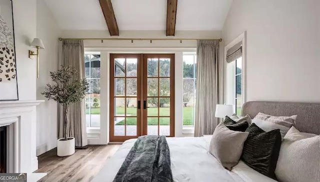 bedroom featuring vaulted ceiling with beams, light wood finished floors, a fireplace, and french doors