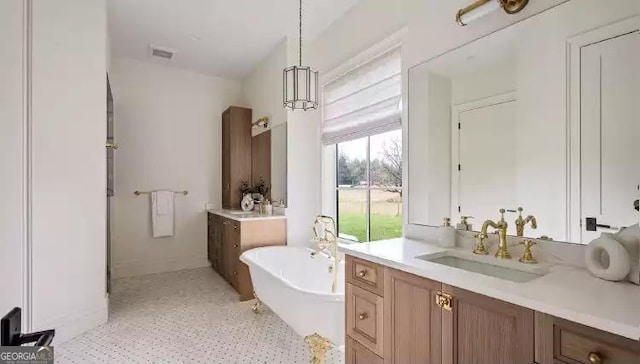 full bath with a soaking tub, visible vents, two vanities, and a sink