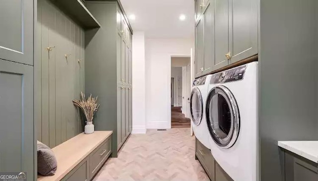 clothes washing area with washing machine and dryer and cabinet space