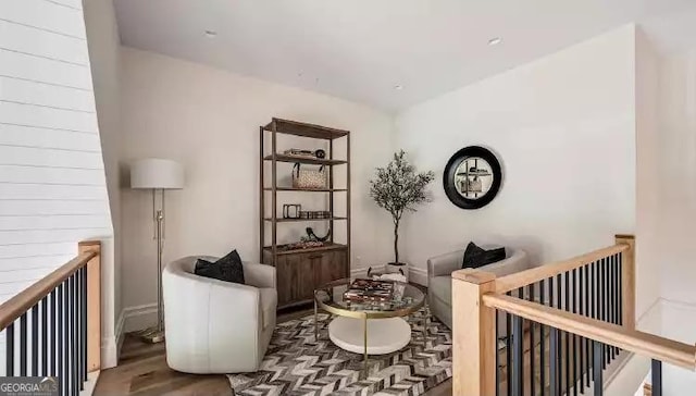 sitting room with wood finished floors and an upstairs landing