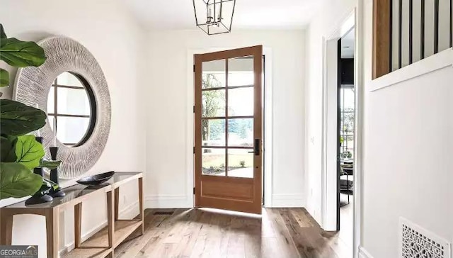 doorway featuring visible vents, baseboards, and wood finished floors