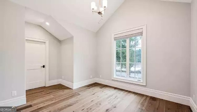 unfurnished room featuring lofted ceiling, wood finished floors, and baseboards