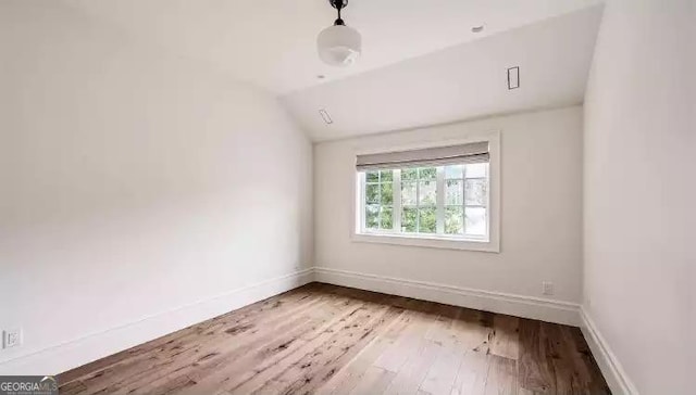 empty room with lofted ceiling, baseboards, and wood finished floors